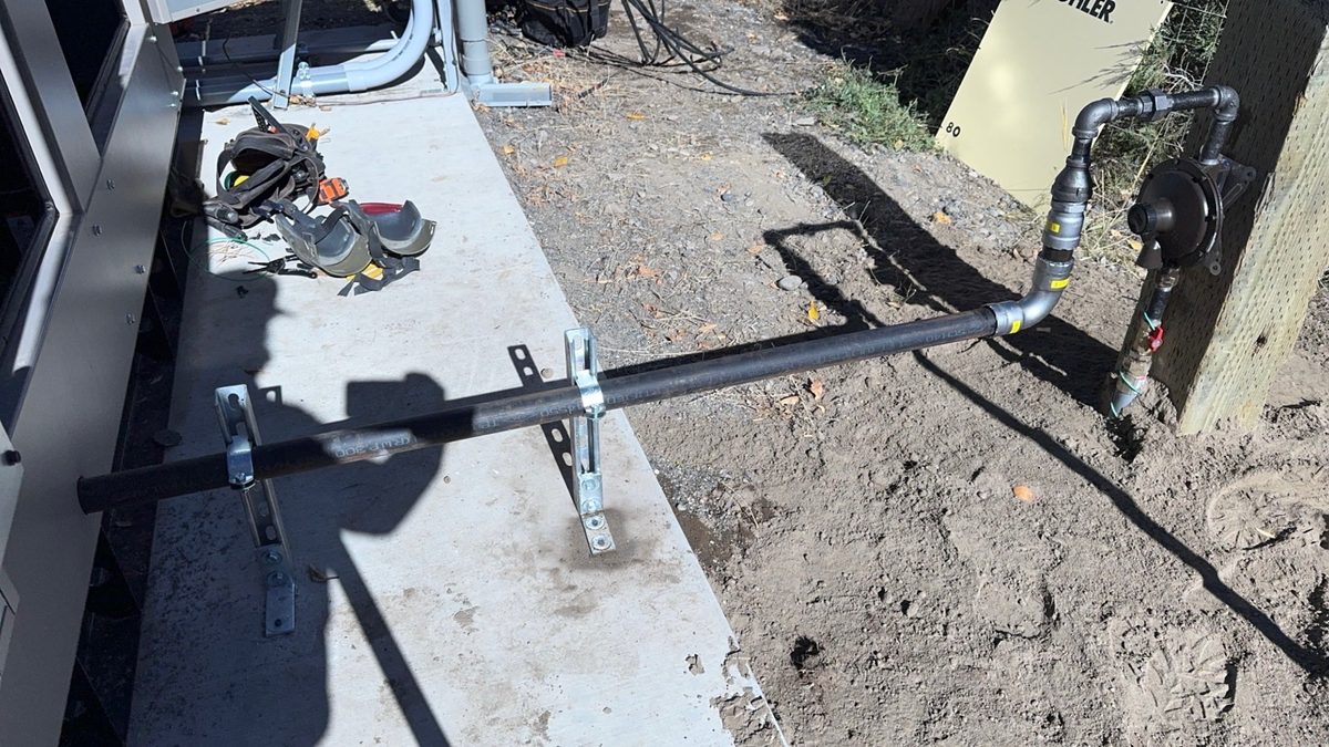 Gas line hookup to Kohler whole-home generator pad with black iron piping