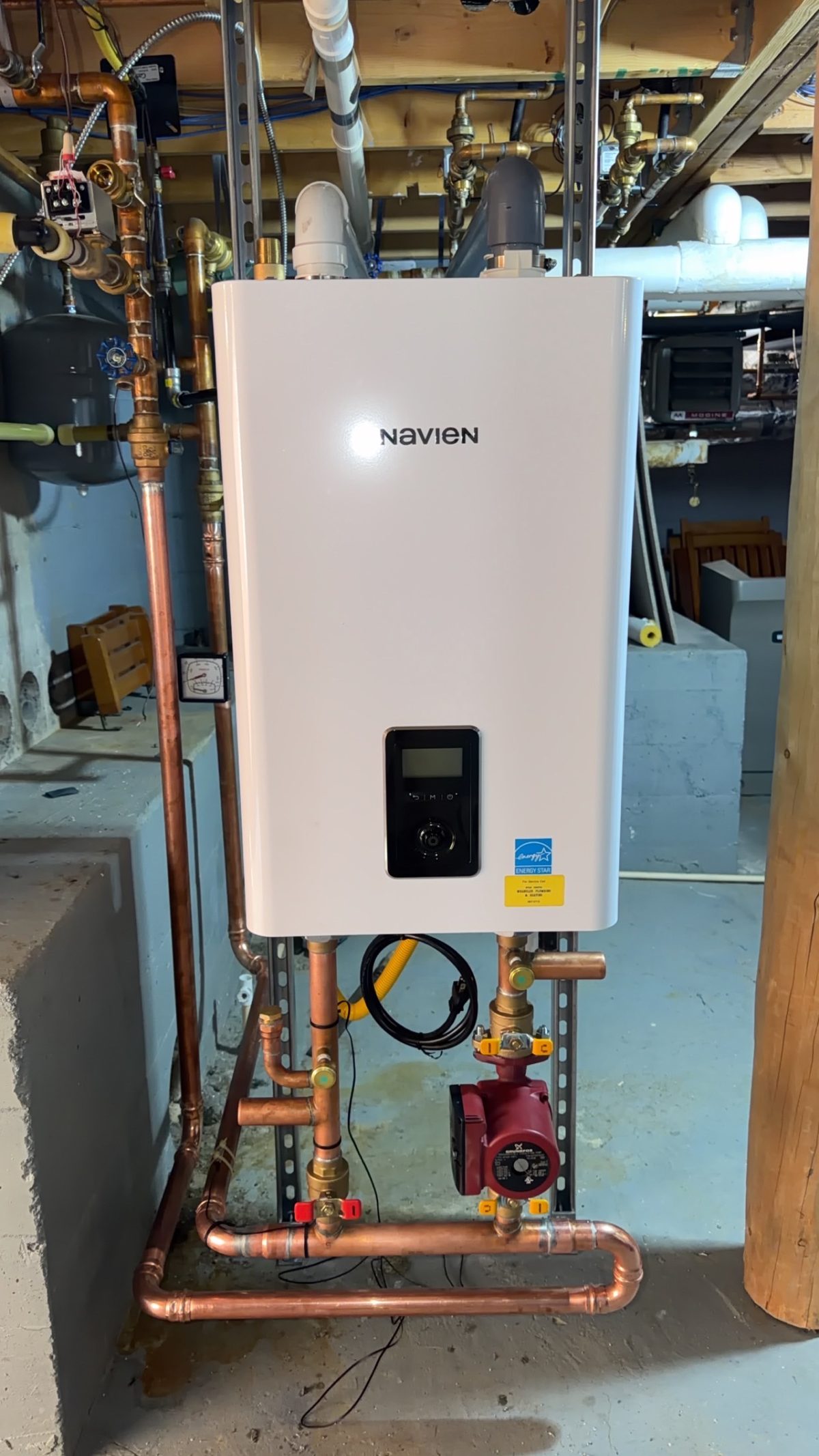 Navien tankless water heater installed in basement with copper piping and Grundfos circulation pump